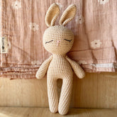 Handmade cream-colored crocheted sleep bunny with closed eyes